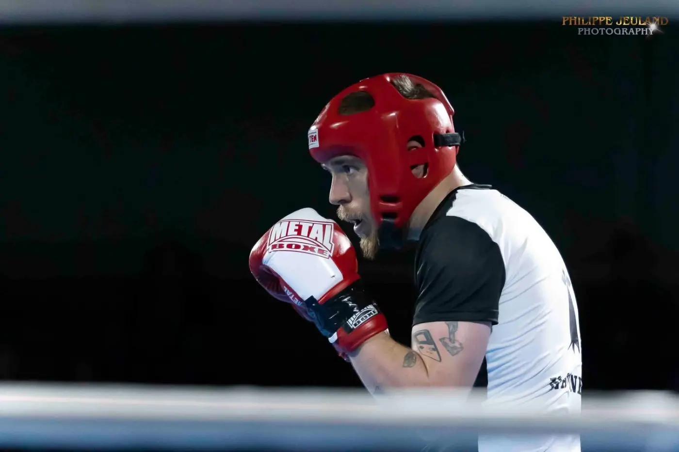 Gros plan sur un combattant en garde, casque de protection et gants de compétition.