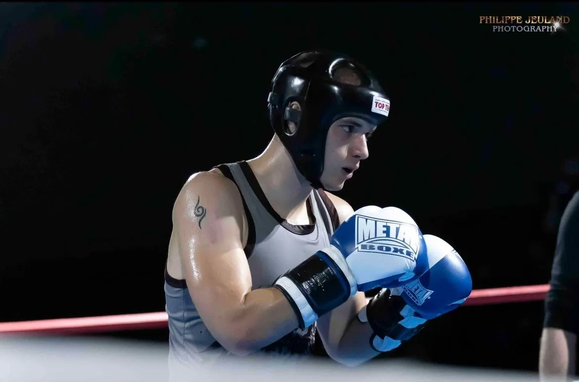 Yann Laurent en garde sur le ring, casque de protection noir et gants de compétition bleus.