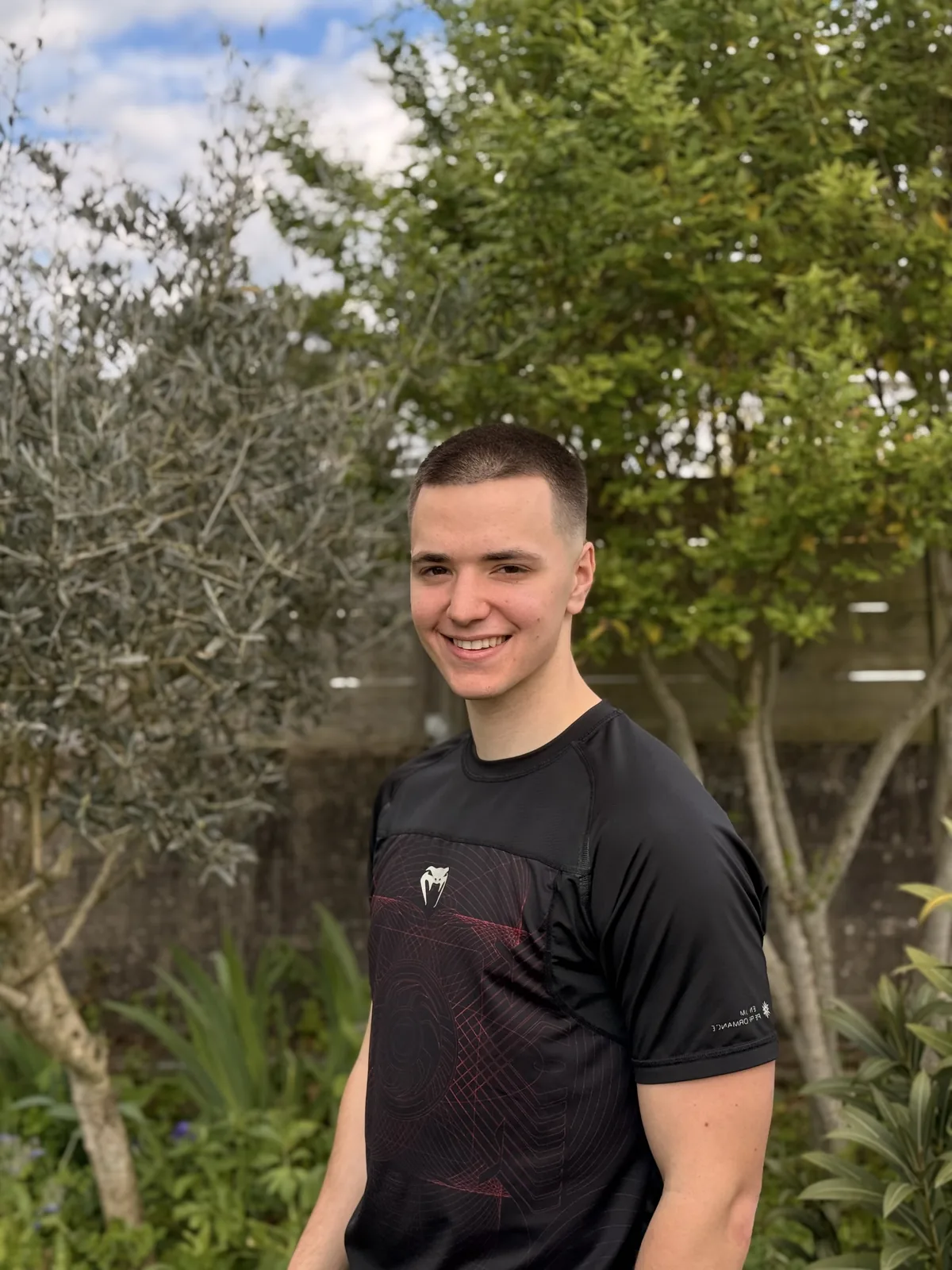 Yann Laurent, souriant, en t-shirt de sport noir, devant des arbres.